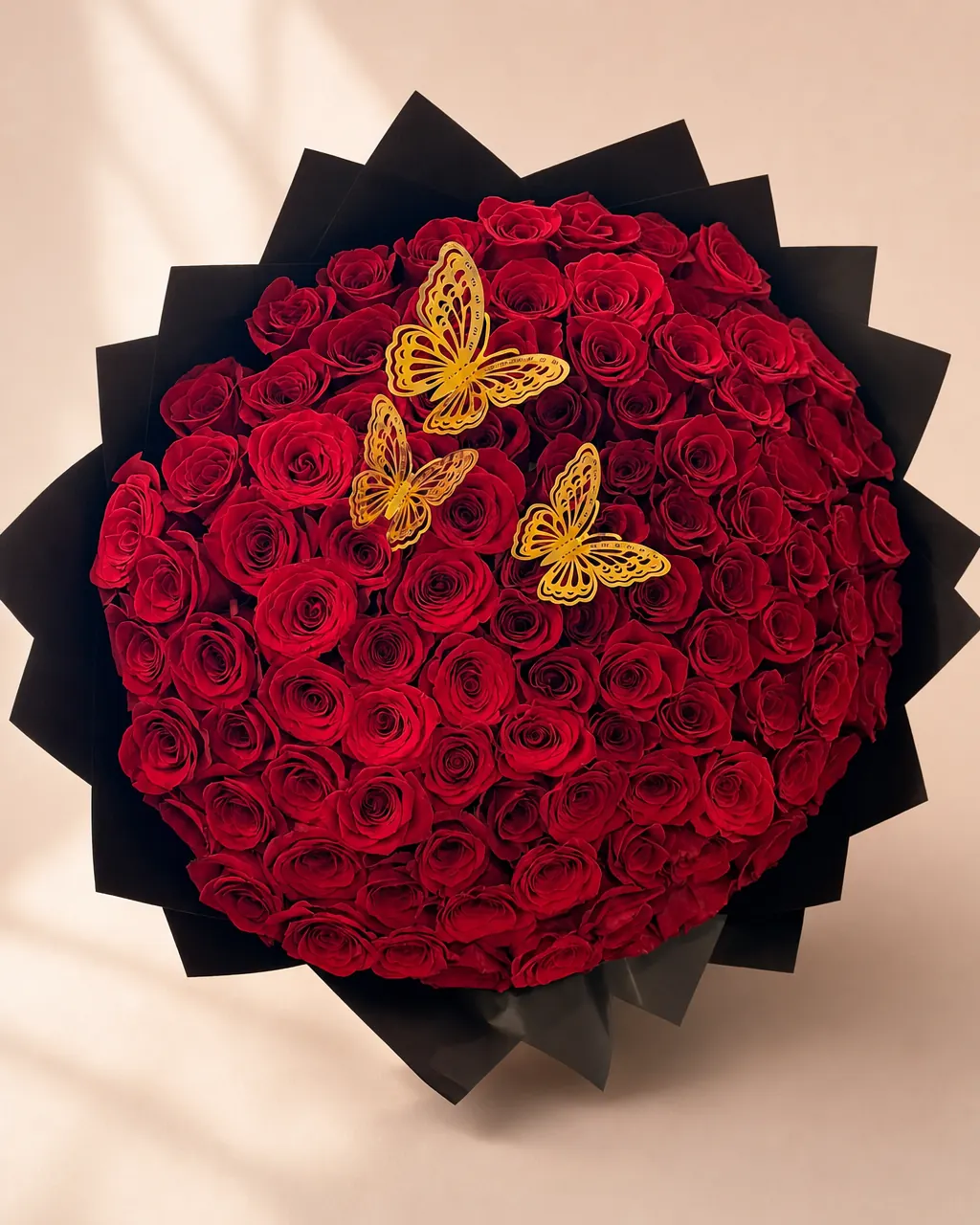 Monarch Night: a round dome of one hundred red roses with gold filigree butterflies, wrapped in pointed black paper