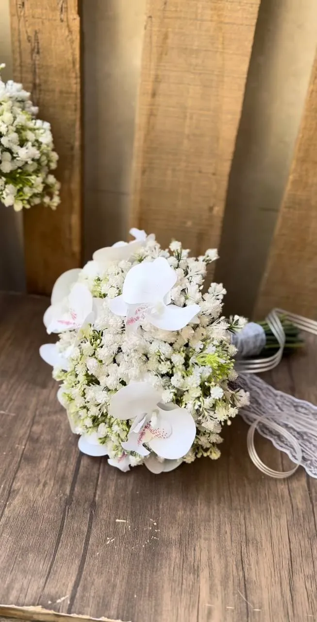 White orchid and baby's breath bridal bouquet resting on a wooden floor