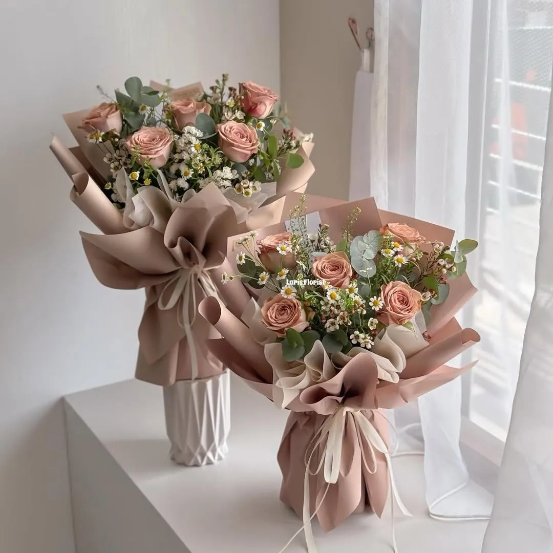 Two bouquets of peach roses, waxflower and eucalyptus in blush wrapping