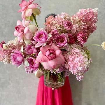Tall pink arrangement of hydrangeas, orchids and roses in a glass vase