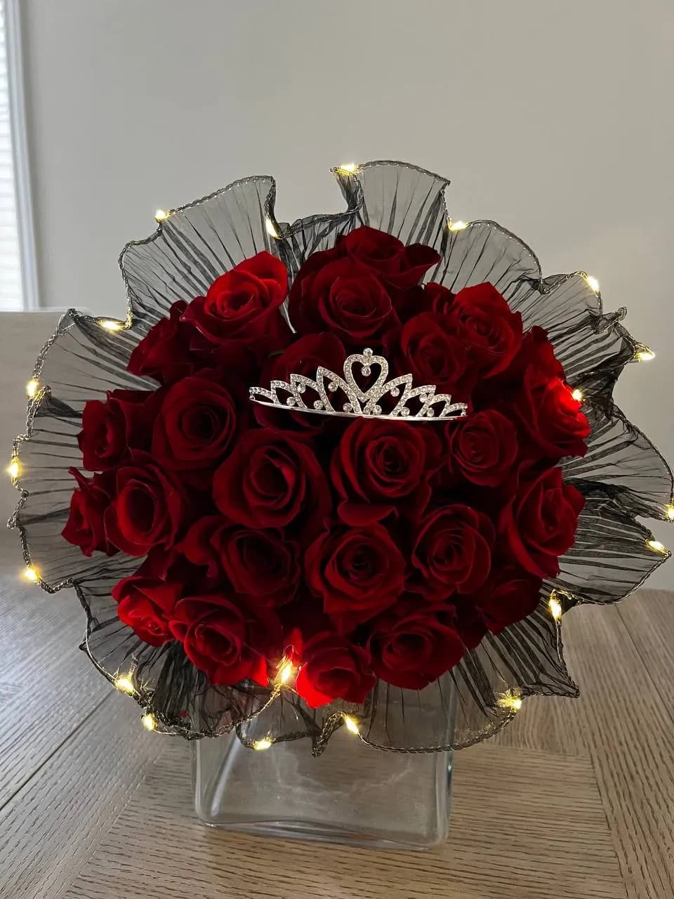 Red roses with a tiara topper, black ruffled wrap and fairy lights