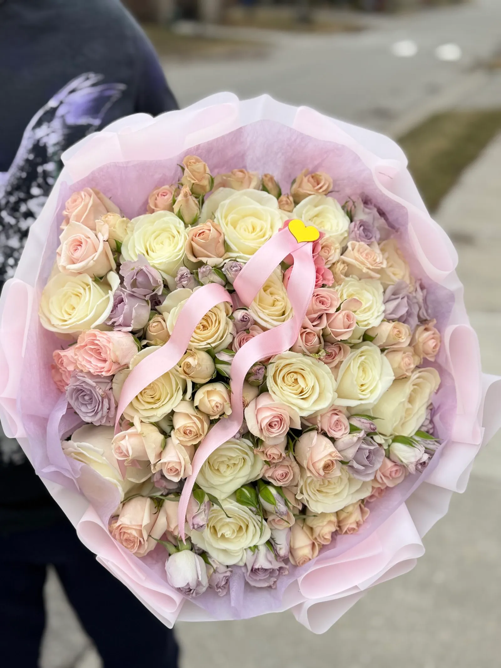 Bouquet of cream, blush and lavender roses with a pink ribbon