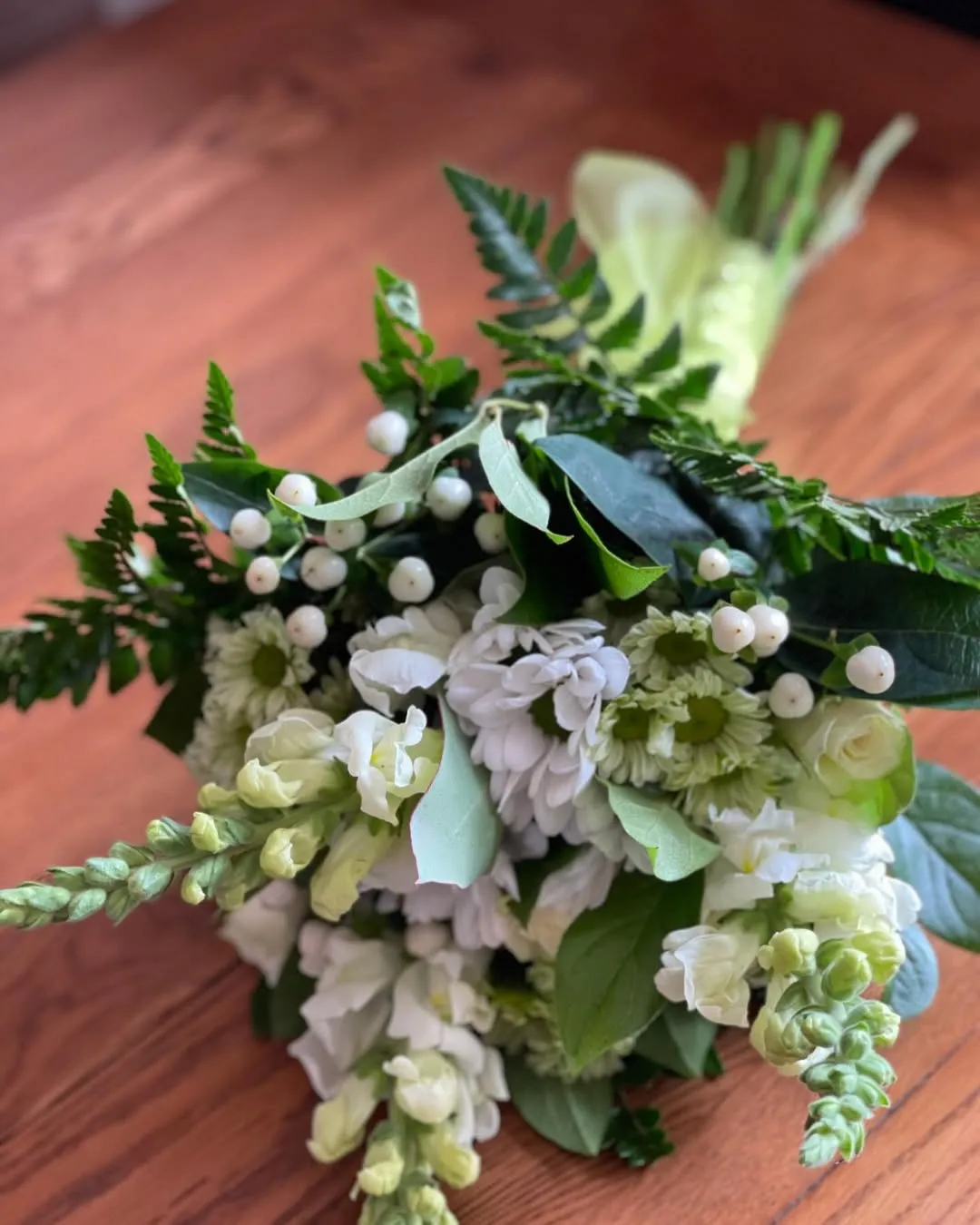Green and white posy with snapdragons, white berries and fern