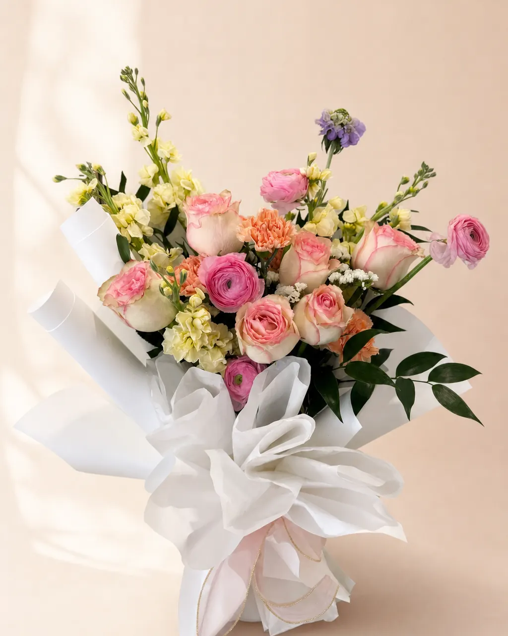 Apricot Sherbet: Pink and peach roses with stock and filler, photographed on a blush backdrop