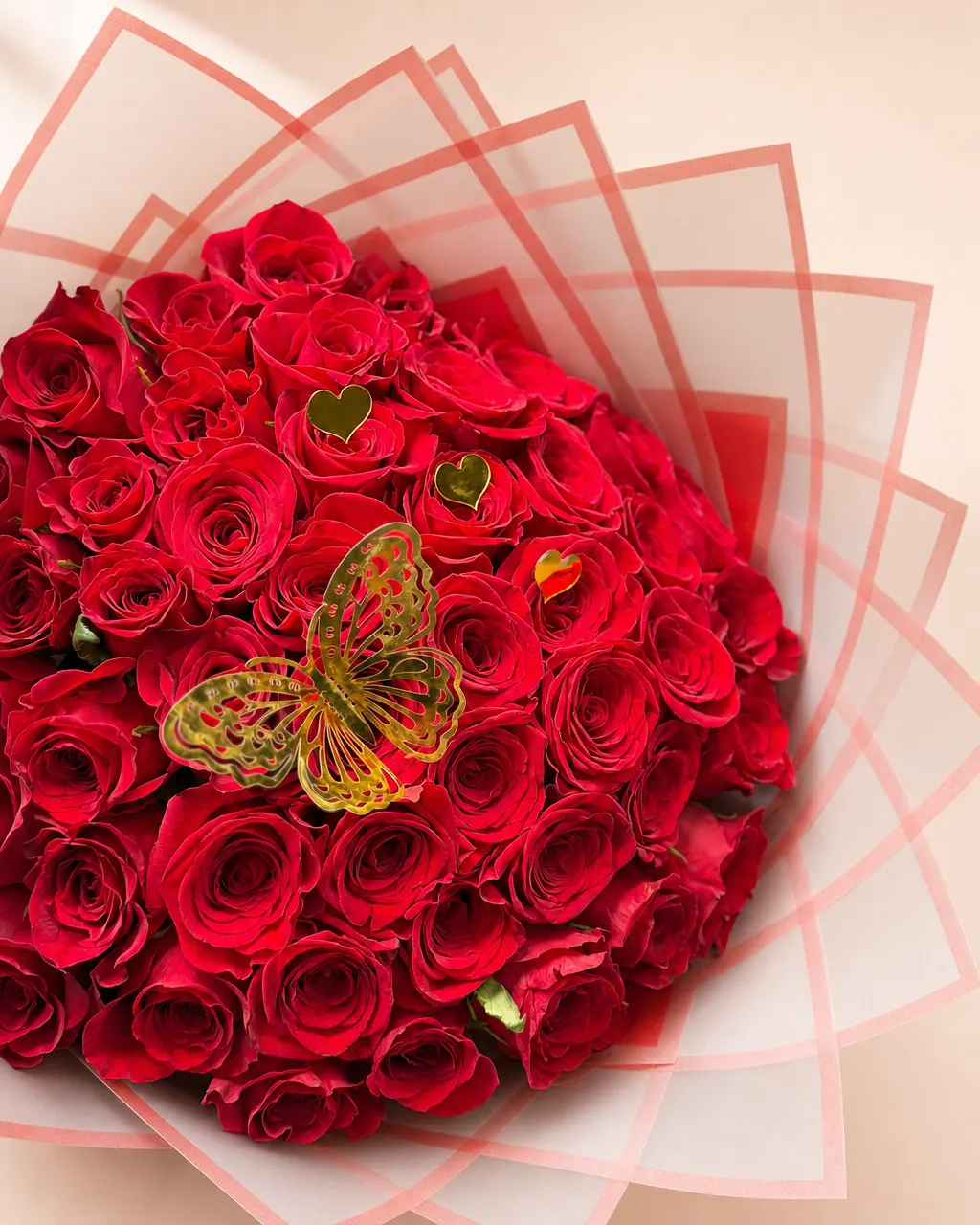 Heart and Wing: red roses with a gold butterfly and small gold hearts in white and coral wrap