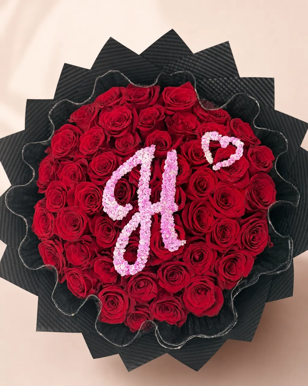Initial in Bloom: 50 red roses with a floral initial, photographed on a blush backdrop