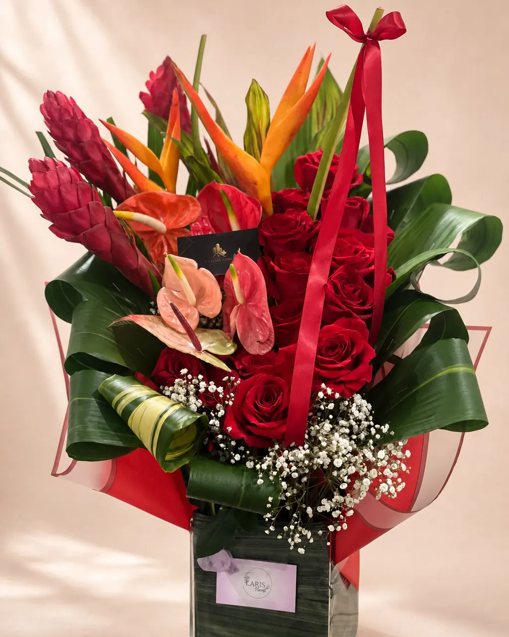 Island Flame: Red roses and tropical flowers in a vase, photographed on a blush backdrop