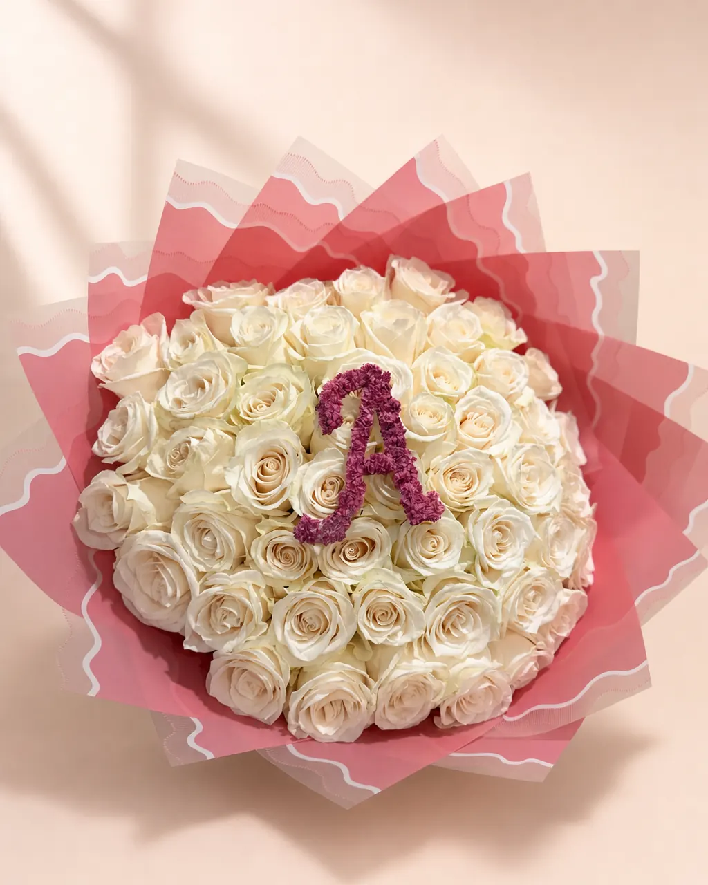 Ivory Script: 50 white roses with an initial, photographed on a blush backdrop