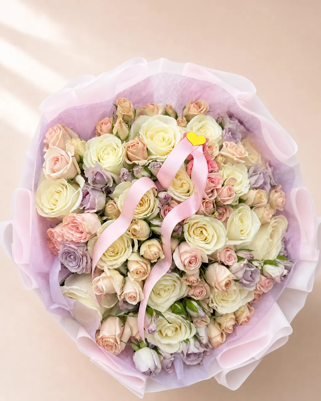 Macaron: 25 white roses with mixed spray roses, photographed on a blush backdrop