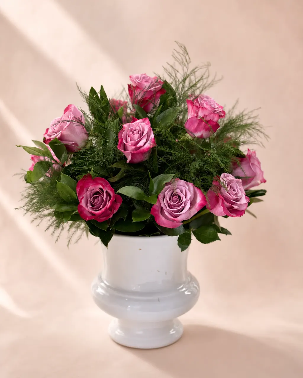 Mauve Pedestal: Roses and greenery in a white pedestal vase, photographed on a blush backdrop