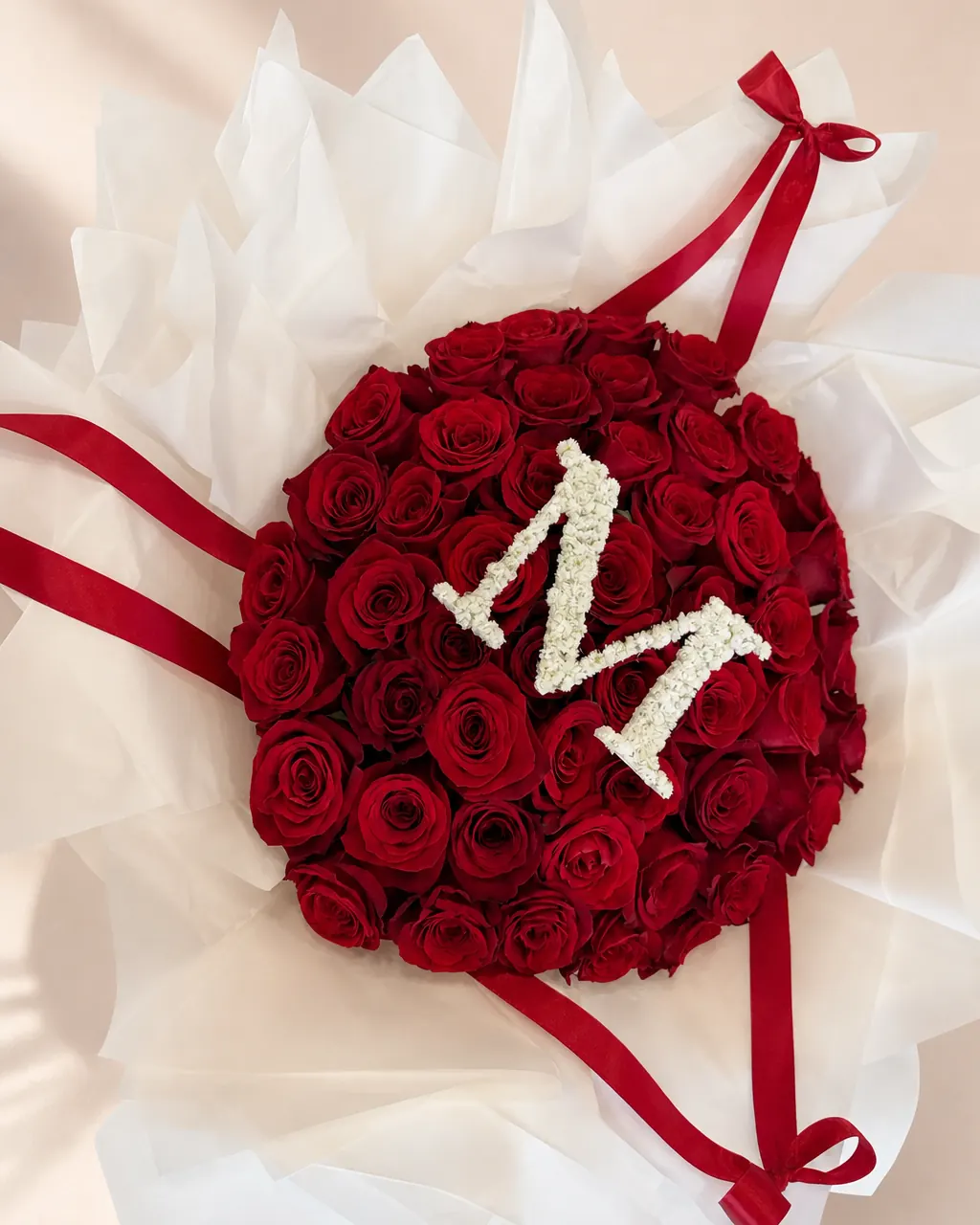 Meringue: 50 red roses, double white wrap and an initial, photographed on a blush backdrop