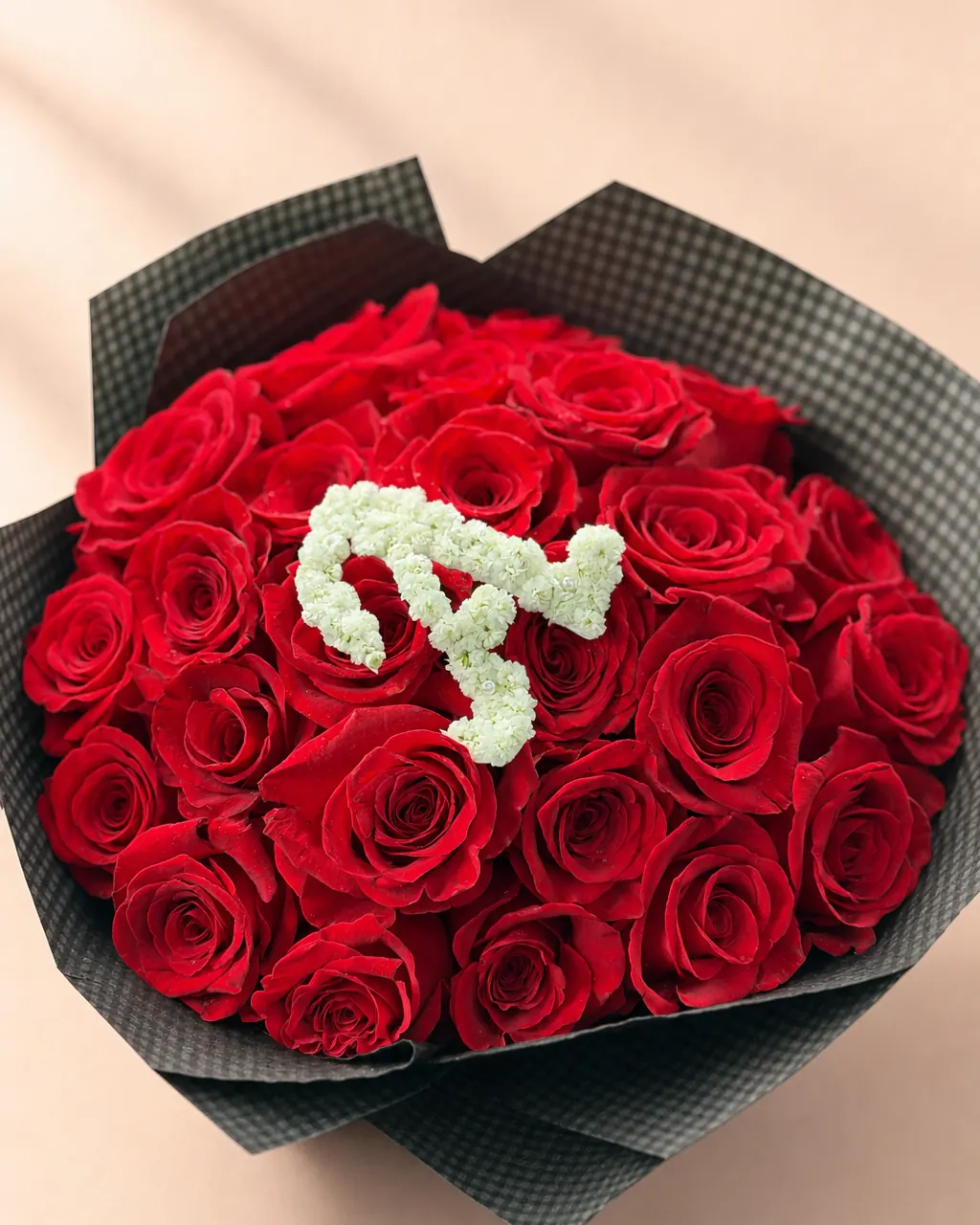 Monogram Noir: 25 premium red roses with a floral initial, photographed on a blush backdrop