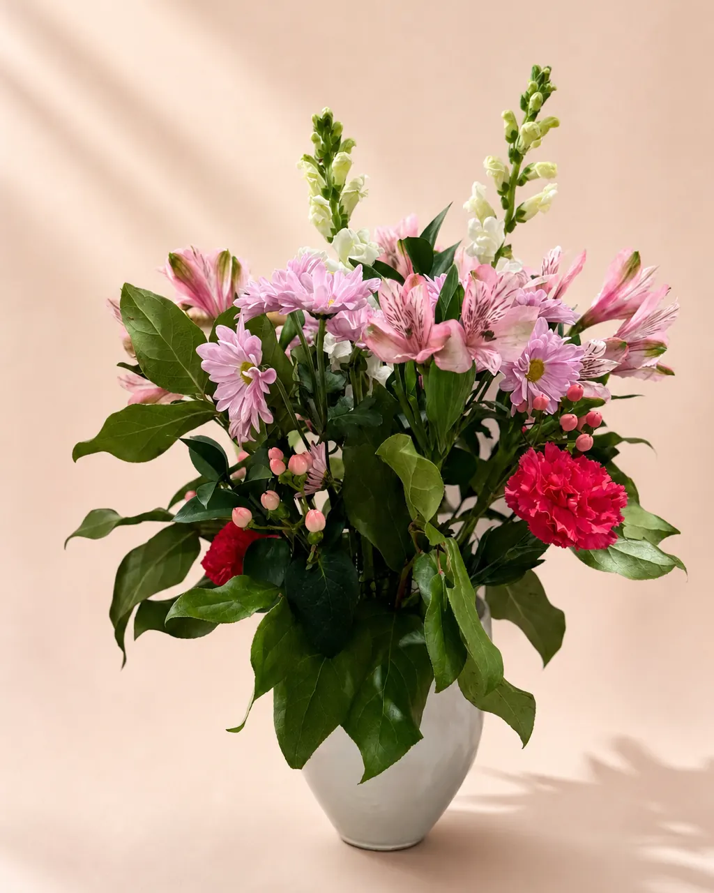 Parlour Posy: Mixed fresh flowers and greenery in a vase, photographed on a blush backdrop
