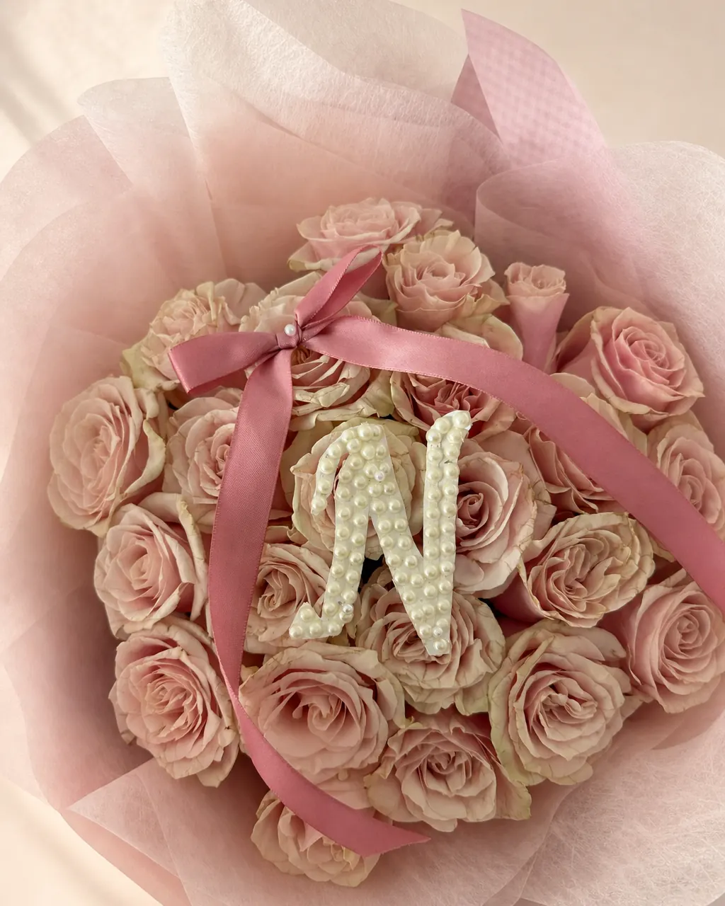 Pearl Signature: 25 pink roses with pearl initial and bow, photographed on a blush backdrop