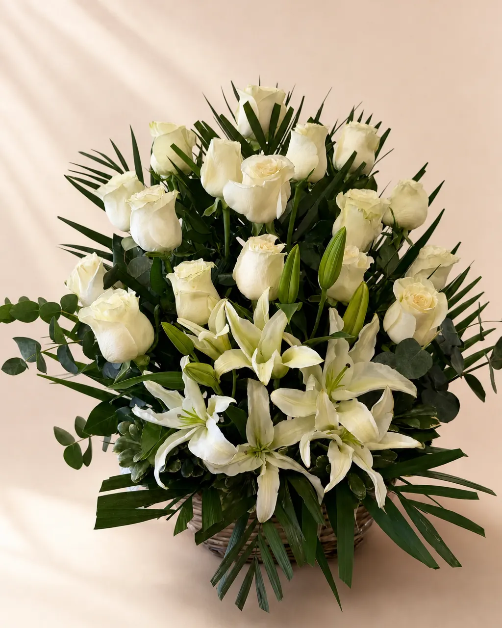 Quiet Lilies: Funeral basket of white roses, lilies and greenery, photographed on a blush backdrop