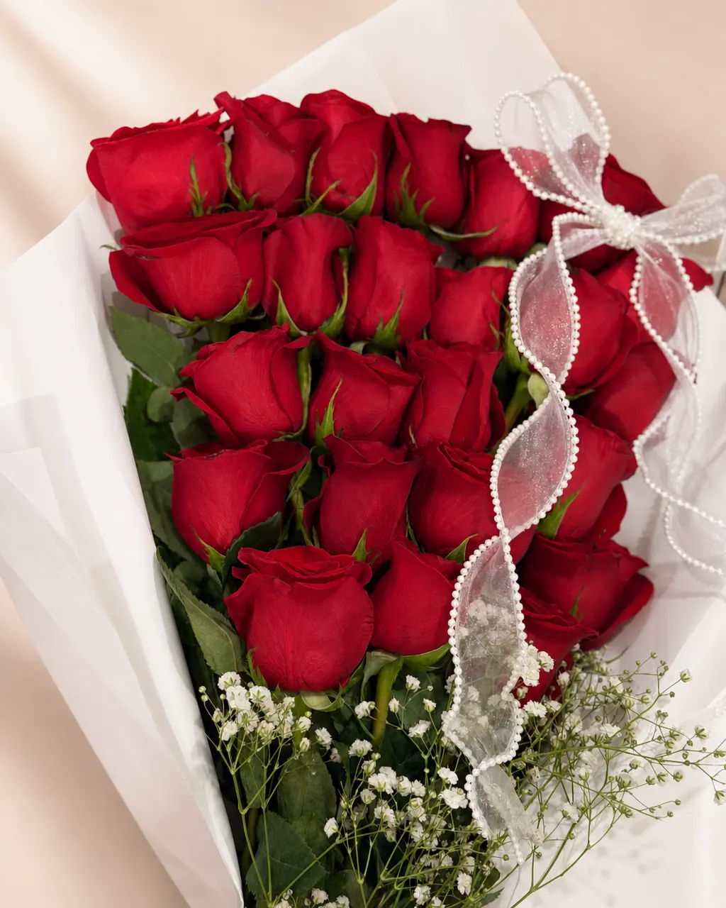 Ribbon Cascade: 20 premium red roses in a flat-style wrap, photographed on a blush backdrop